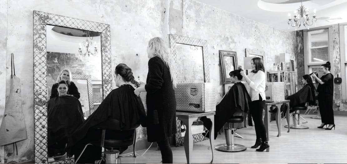 Empire Beauty School students performing hair services in a trendy salon